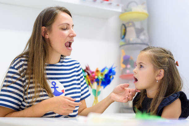 A speech therapist working with a child using picture cards
